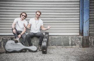 Das Duo „TwoForTwelve“ sitzt vor einer Garage