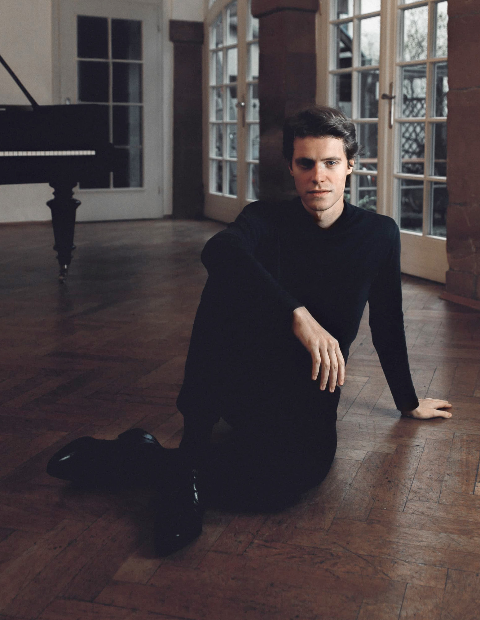 Ein Pianist sitzt vor einem Flügel auf dem Boden