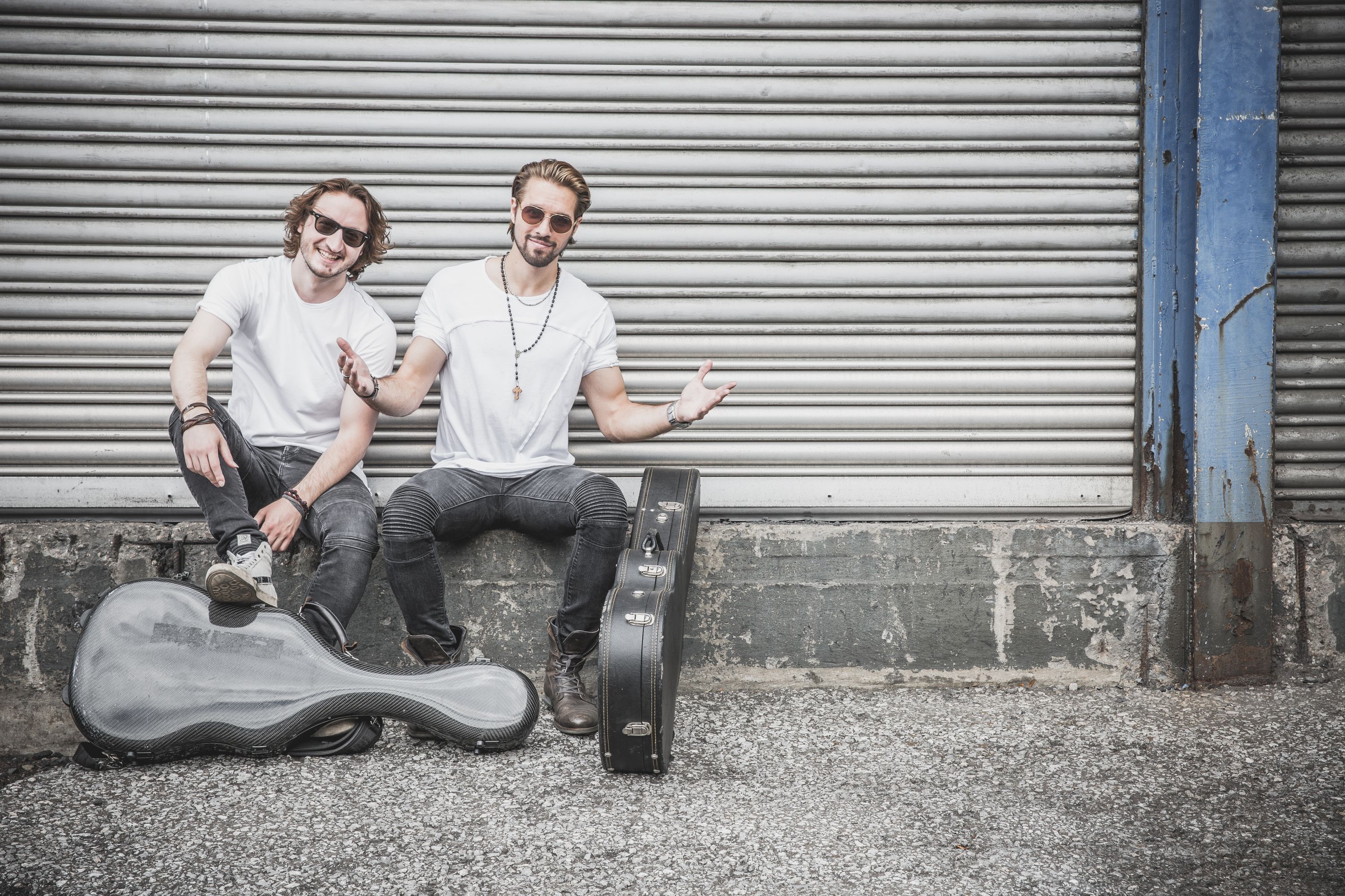 Das Duo „TwoForTwelve“ sitzt vor einer Garage